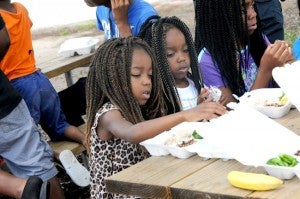 Powell Cobb — Post-Searchlight complete meal: Kids open up their lunches Tuesday at BPS headquarters, where the Kids n Kops program provided hot meals to local youth who may not have a complete meal otherwise during the summer months